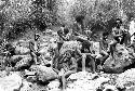 Men and children watching from the rocks above the salt well as women and others work in the pool