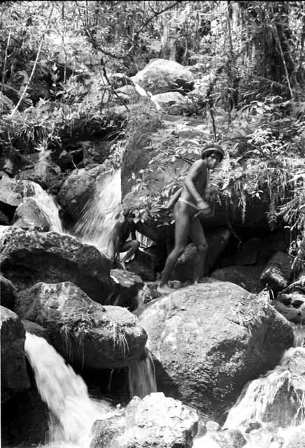 Man walking along the boulders in the stream bed