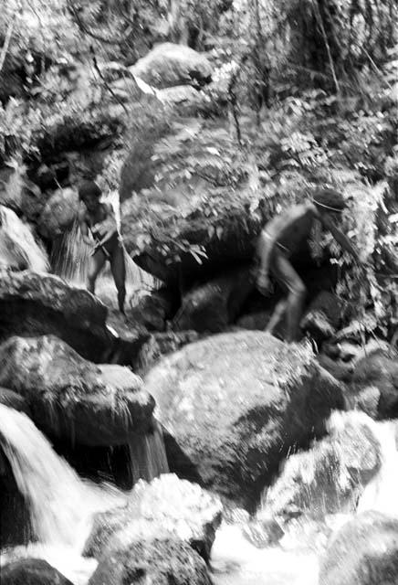 Man walking along the boulders in the stream bed