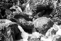 Water rushes over the rock; man sits to drink