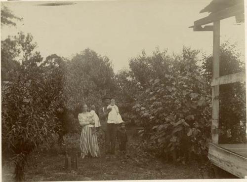 View of husband and wife each carrying a baby girl and little boy standing