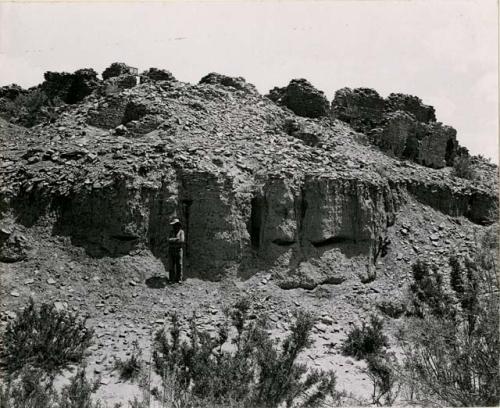 Indian man standing in front of outer southwest corner before excavation