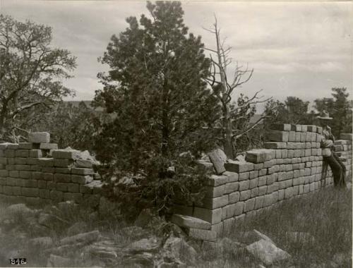 Man leaning against partially ruined stone wall