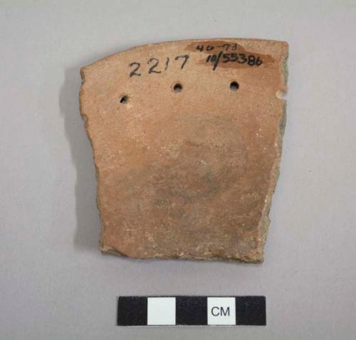 Perforated plate sherd; more polished on interior; three complete perforations (1.9 cm.) from rim edge; two broken perforations along edges; plainware.