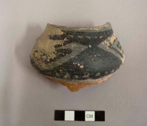 Rim sherd; jar; interior unslipped; exterior worn, broad design band near rim, black-on-white with basal red slip; gila polychrome.