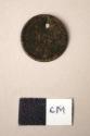 Metal, bead, coin, one perforation at edge, one side has image of masted ship wi