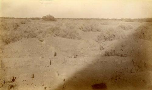 Ruin III. Looking East.  Large room with door step.  Fire bowl, concrete roof support in center