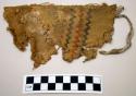 Woven fabric fragment, possibly cotton, painted with black and red zig zag lines
