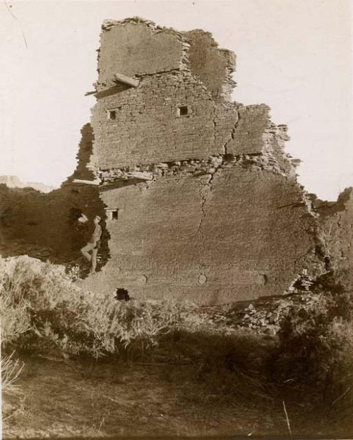 Ruins of Pueblo with man leaning against side