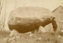 Big boulder propped on rocks and man standing beside it