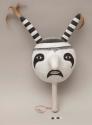 Hopi clown rattle; gourd with painted black and white face; applied black and white striped elements at top with feathers; on wooden handle