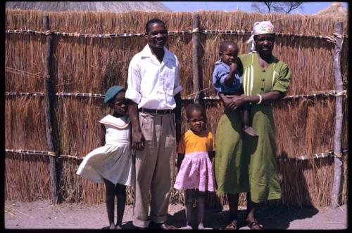 Ledimo, his wife and three children standing by their fence