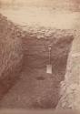 Excavated ledge of large mound showing covering of stone.