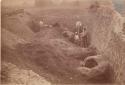 Men excavating section of large mound.