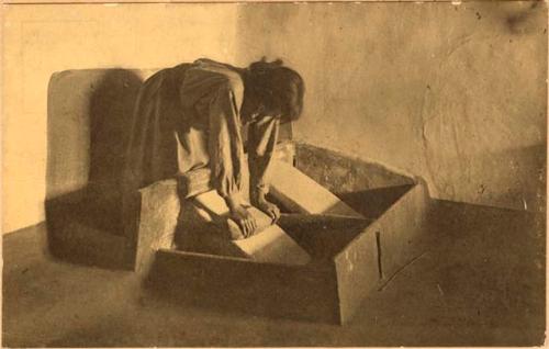 Indian woman grinding corn on a metate