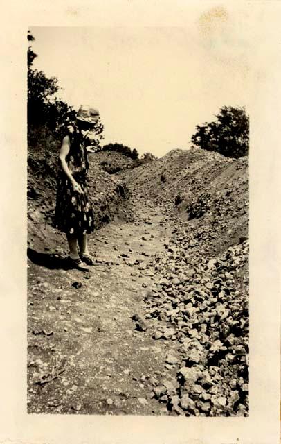 Woman standing near trench site and mound