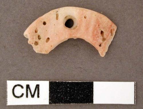 Shell, flat, crescent shaped fragment with perforation at center