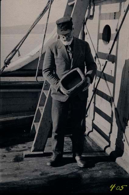 Man aboard ship, holding vessel. Members of Explorer's Club on expedition