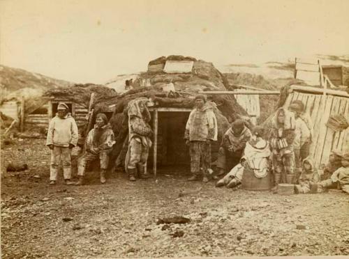 Group of Inuit people in front of sod house