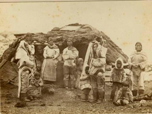 Group of Inuit people in front of sod house