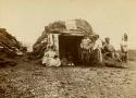 Inuit family in front of log and sod house
