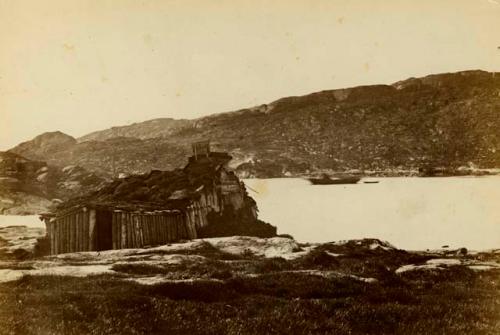 Log and sod building on rock out crop above inlet