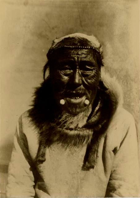 Inuit man wearing labrets and skin cap.