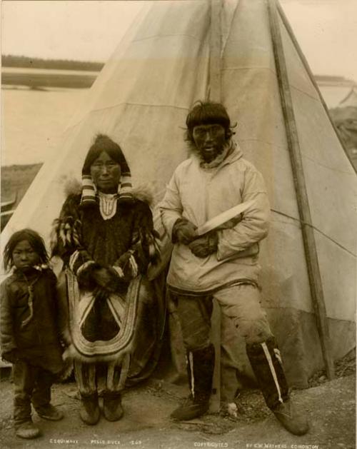 Inuit man, woman and a child in front of tent