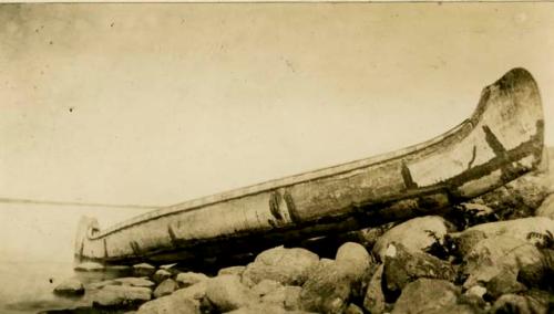 Bark canoe pulled up on shore, showing mends