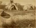 Group of Cree people in camp, with canoe in foreground