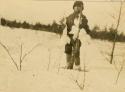 Montagnais boy holding a rifle and three white birds