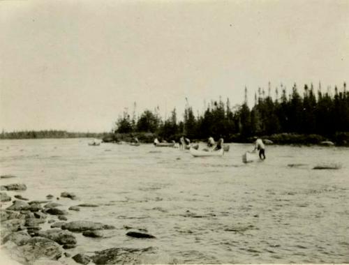 Wading canoes up shallow waters. St. Augustin Indians.