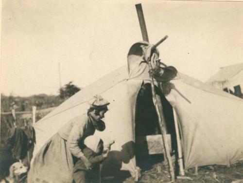 Woman with small child in front of canvas tent. Note: woman's hat