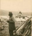 Man in encampment, structure in background