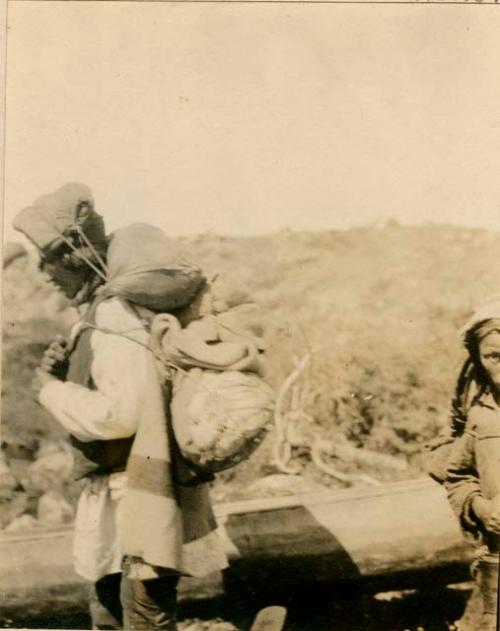 Naskapi man with bundle on back - using head harness to hold it up.