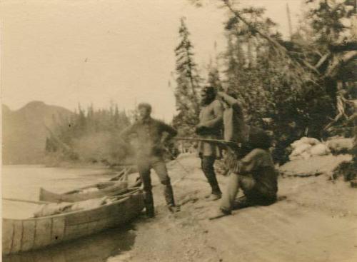 Three Naskapi men and another man with two canoes pulled on shore