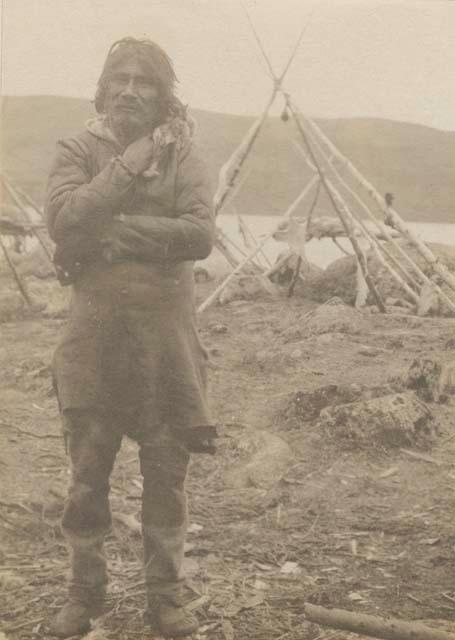 Naskapi man; tepee frame in background.