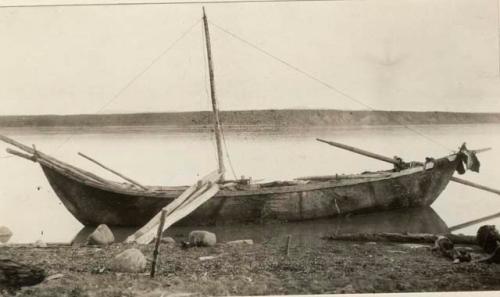 Skin boat near bank, poles used to anchor boat.