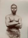 Studio portrait of an Aboriginal man, arms crossed and wearing an animal pelt
