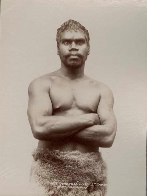 Studio portrait of an Aboriginal man, arms crossed and wearing an animal pelt