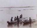 Group of Aboriginal males in a canoe and standing in water