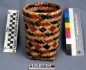 Cylinder basket, double weave, of split cane, square base. Canes dyed red and bl