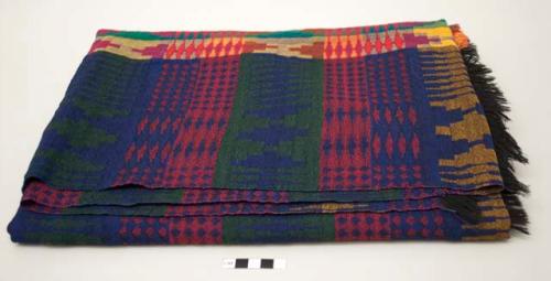 Woven textile; mostly dark green, dark red and indigo geometrics; section of brighter colors