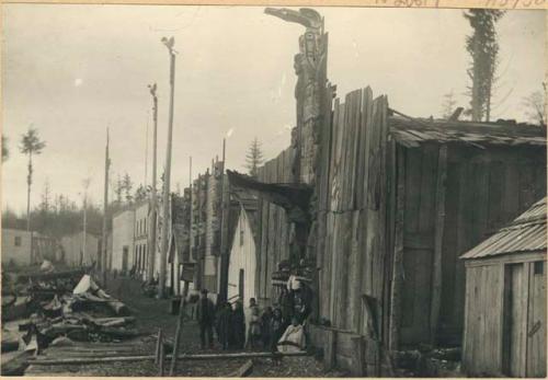 Old house with totem pole, projecting bow of large canoe destroyed at potlatch