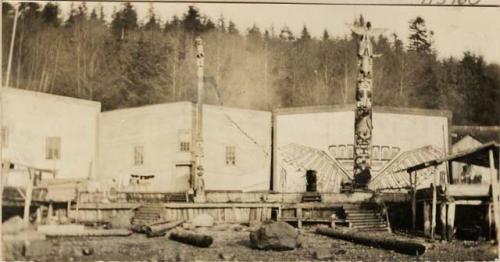 Two totem poles in village setting