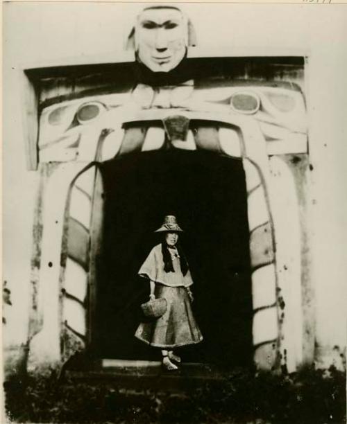 Quatsino woman wearing cedar bark dress and standing in doorway