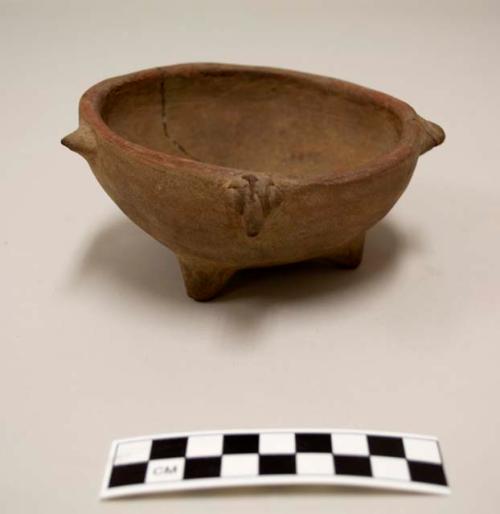 Ceramic Tripod vessel, four knob handles or appliques, one of which is zoomorphic head, red pigment at rim