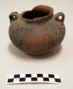 Ceramic jar, two strap handles, exterior is red and black with incised and punctate decoration on body, series of small oval appliques with punctate decoration around rim