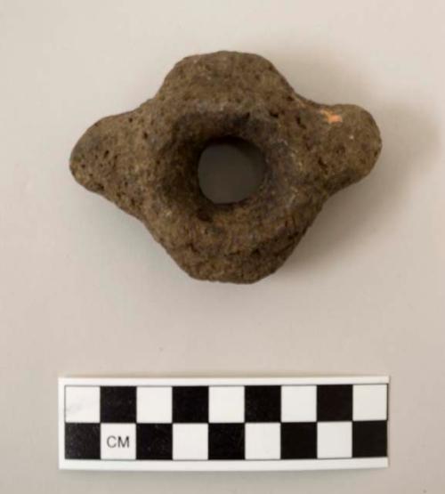 Disc shaped perforated ground stone object with knob-like protrusions on opposite sides