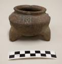 Tripod vessel, small triangular feet, incised and punctate design, constricted neck, flared rim, some red pigment